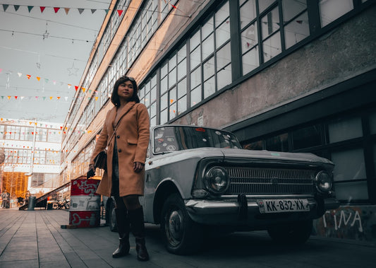 Une femme porte un manteau mi-saison femme vintage debout près d'une voiture dans la rue en ville.