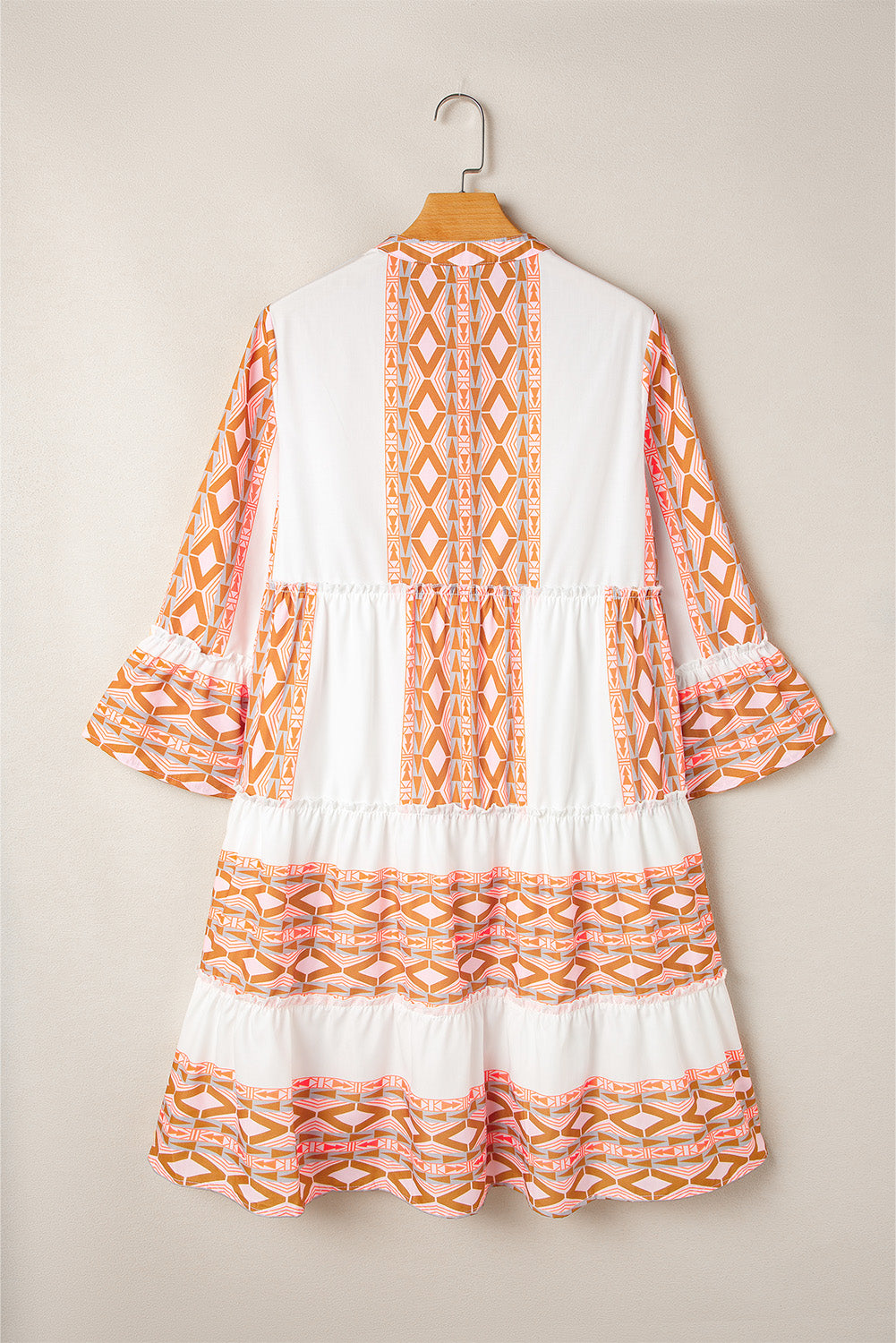 Robe orange à col en V et boutons à volants et imprimé géométrique