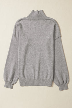 Pull en tricot gris à col roulé, épaules tombantes et manches bulles