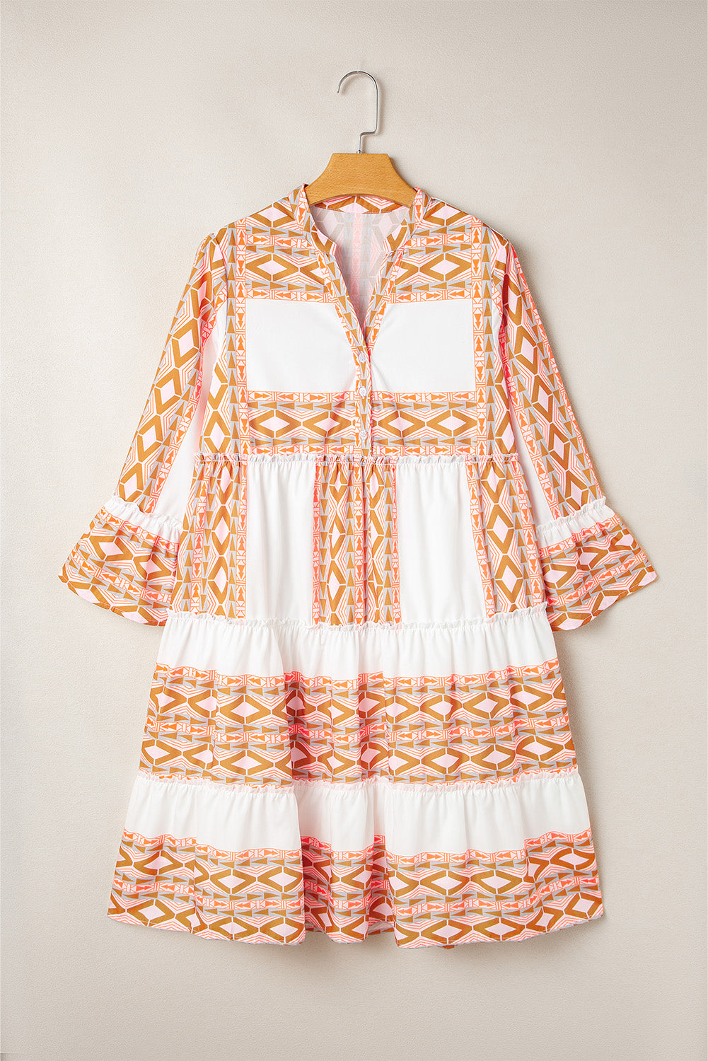 Robe orange à col en V et boutons à volants et imprimé géométrique