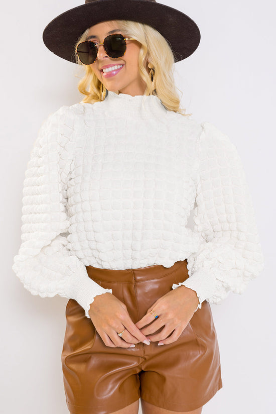 White textured top with puff sleeves and smocked mock neck