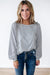 Light gray long sleeve sweater top with raw hem in waffle patchwork