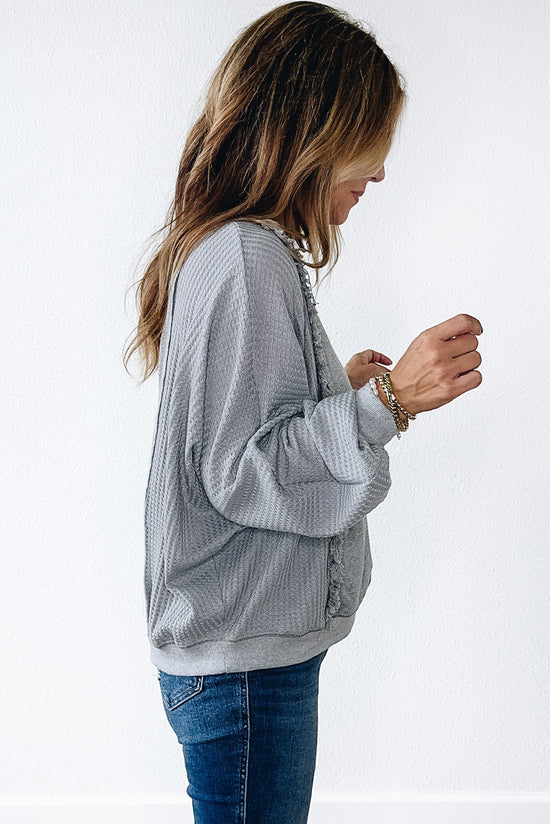 Light gray long sleeve sweater top with raw hem in waffle patchwork