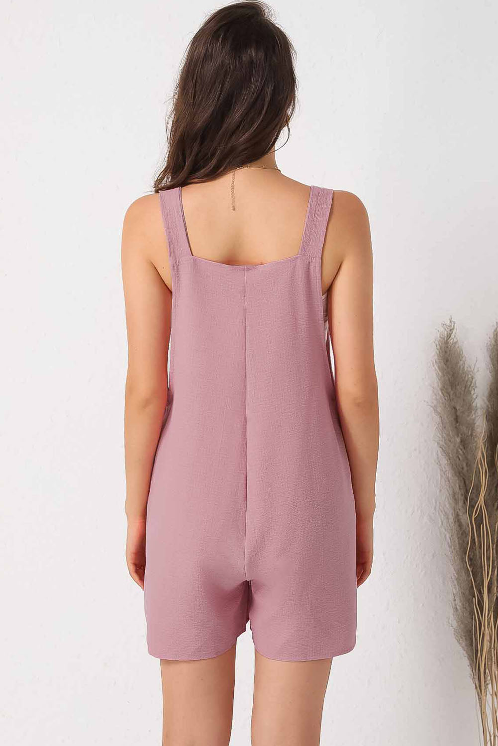 Pink textured romper with adjustable straps and pockets