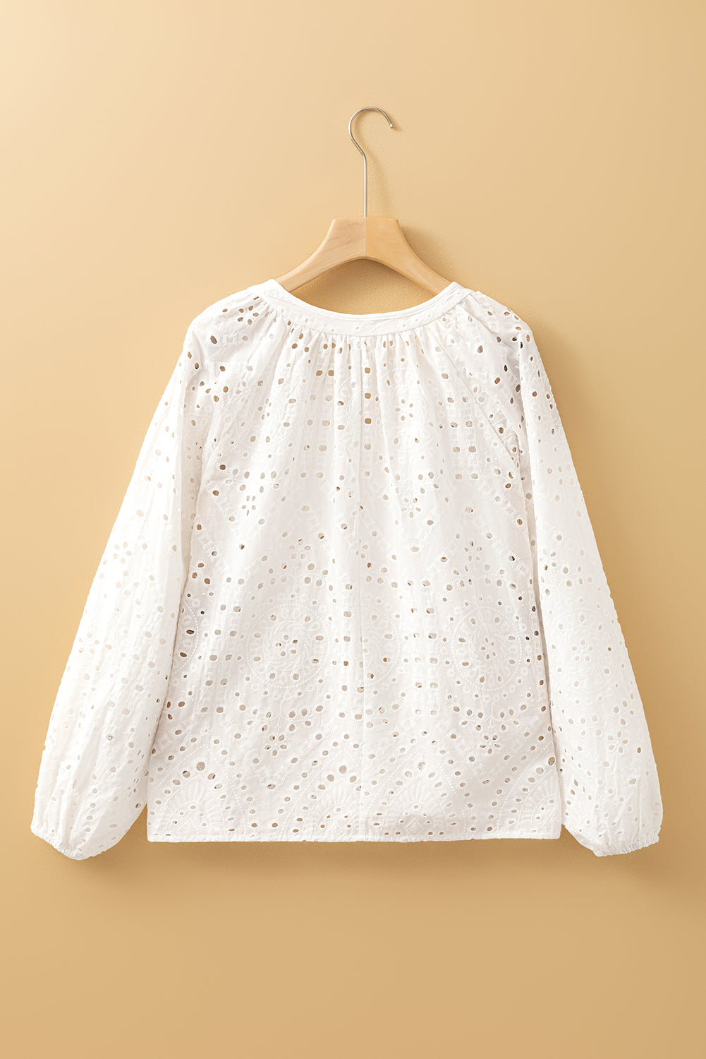 Blouse blanche à col en V et manches bouffantes brodées d'œillets