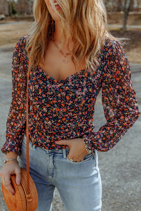 Blouse florale noire à col en V et manches bouffantes