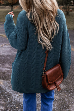 Cardigan baggy bleu paon en tricot torsadé boutonné avec poches sur le devant