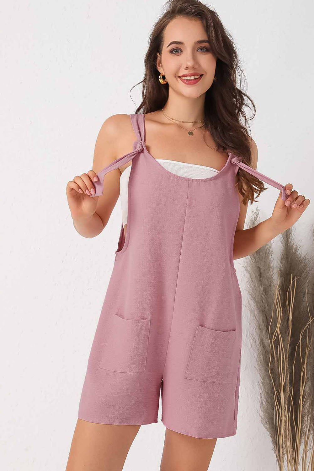 Pink textured romper with adjustable straps and pockets