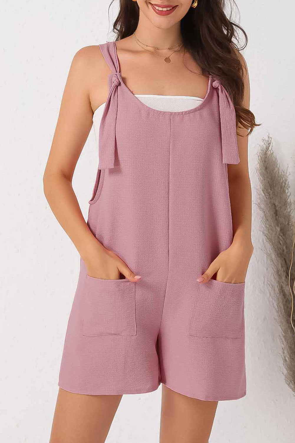 Pink textured romper with adjustable straps and pockets