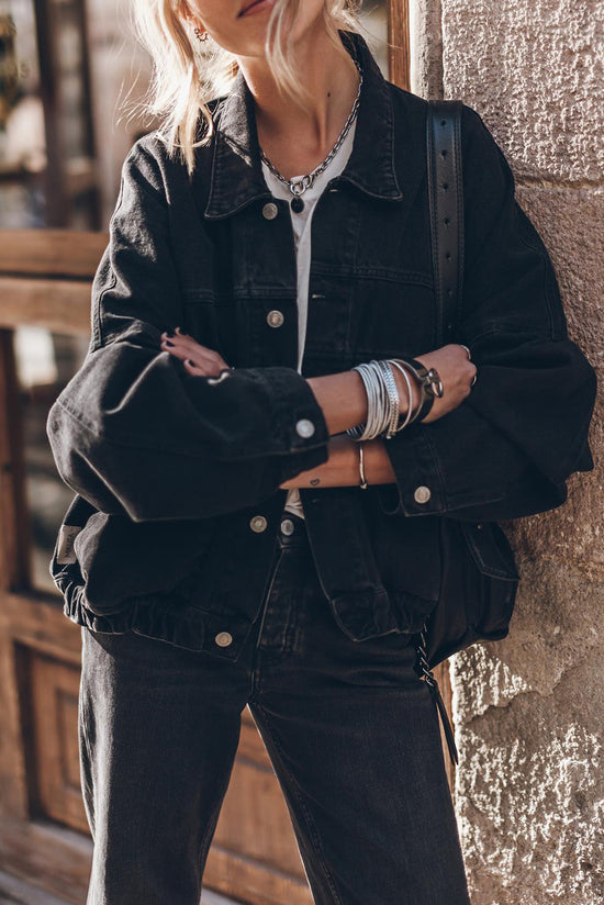 Black denim jacket with flap pockets and dropped shoulders with metal buttons