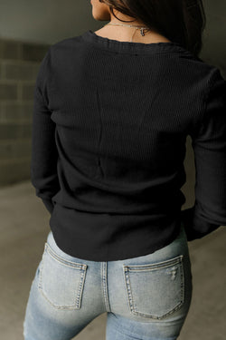 Alto Henley en tejido negro en relieve con un escote fronterizo