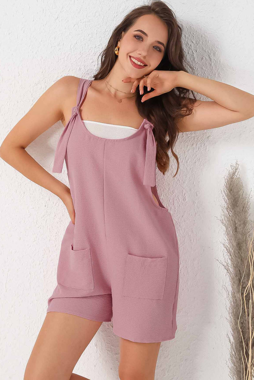 Pink textured romper with adjustable straps and pockets