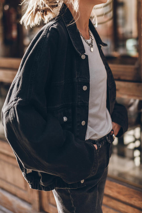 Black denim jacket with flap pockets and dropped shoulders with metal buttons