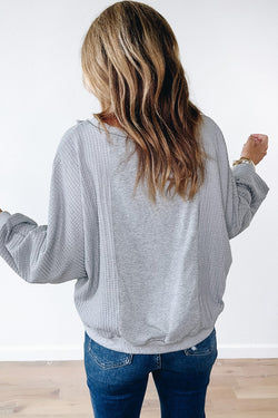 Light gray long sleeve sweater top with raw hem in waffle patchwork