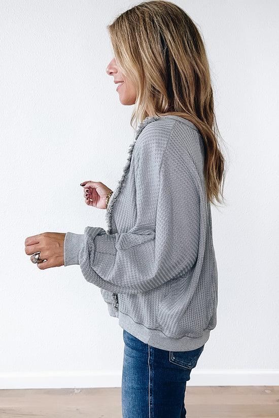 Light gray long sleeve sweater top with raw hem in waffle patchwork