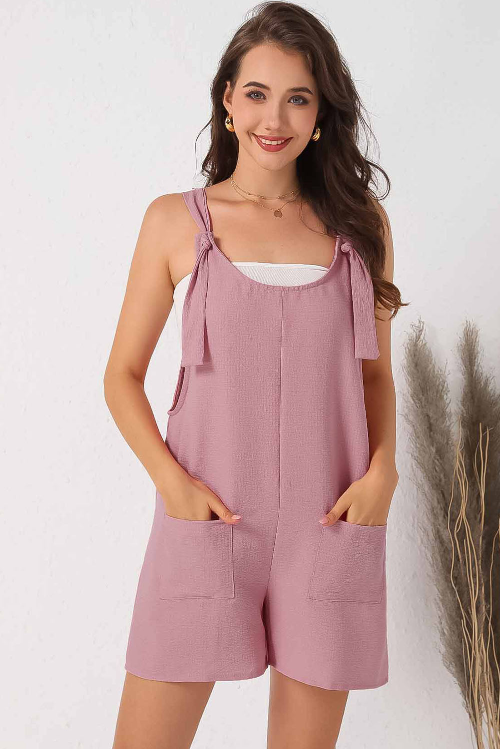 Pink textured romper with adjustable straps and pockets