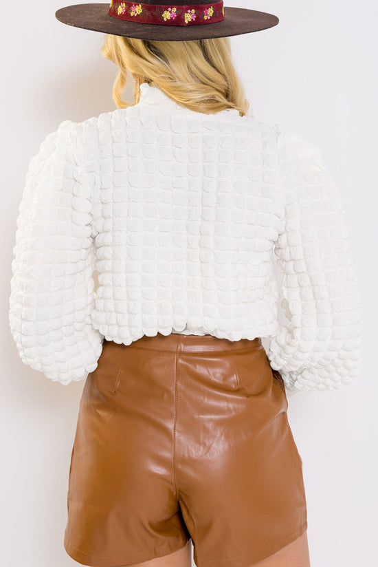 White textured top with puff sleeves and smocked mock neck