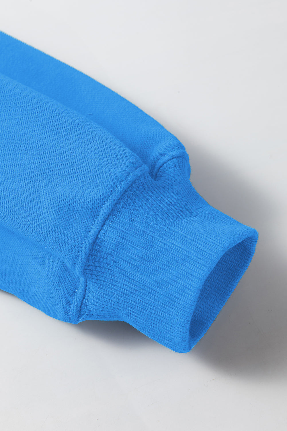 Sudadera básica con manga larga y hombros que caen en un cielo azul liso