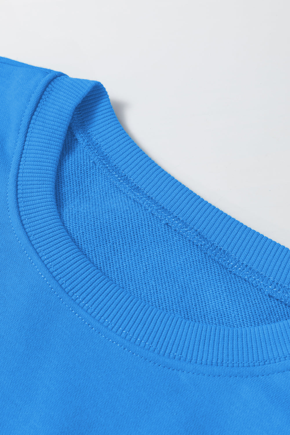 Sudadera básica con manga larga y hombros que caen en un cielo azul liso