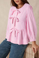 Striking pink blouse and bow tie on the front, round neck, puffy sleeves