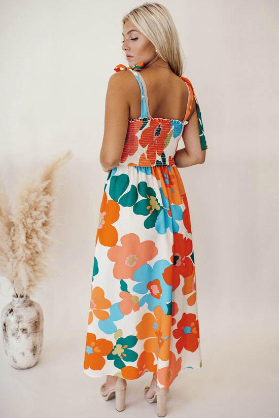 Long orange floral dress with straps tied at the smocked bust