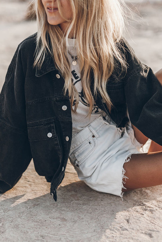 Black denim jacket with flap pockets and dropped shoulders with metal buttons