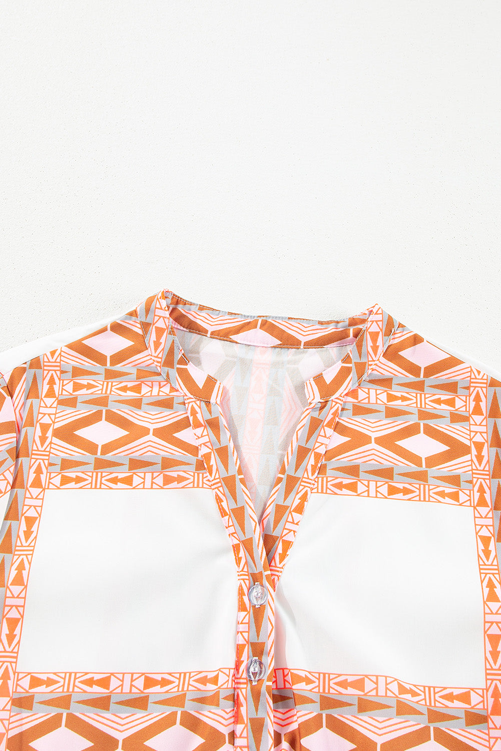 Robe orange à col en V et boutons à volants et imprimé géométrique