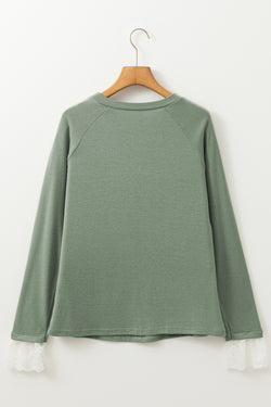 Grass green top with raglan sleeves and contrasting lace cuffs with contrasting stitching